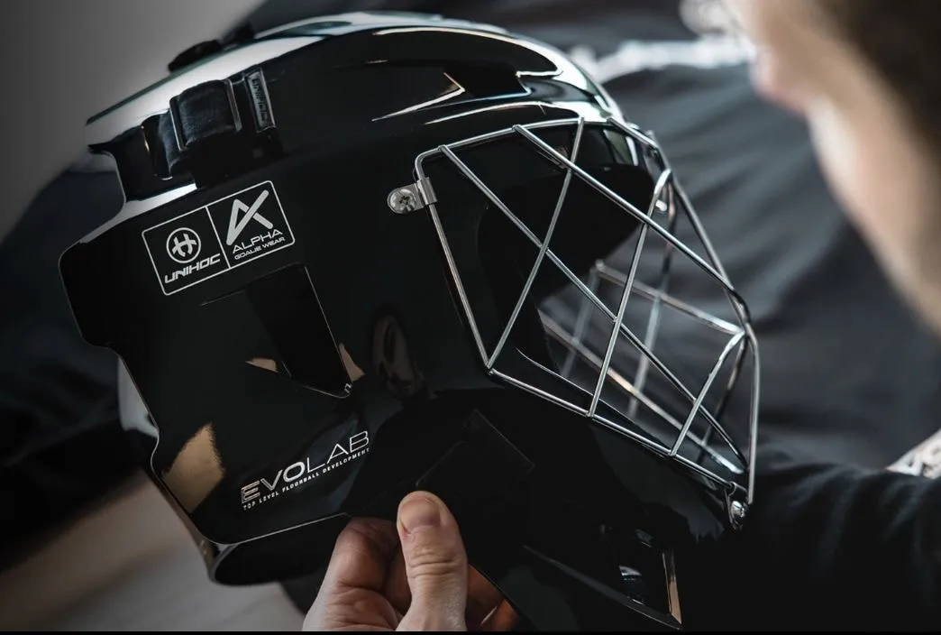 A goalkeeper helmet being held up close to the camera