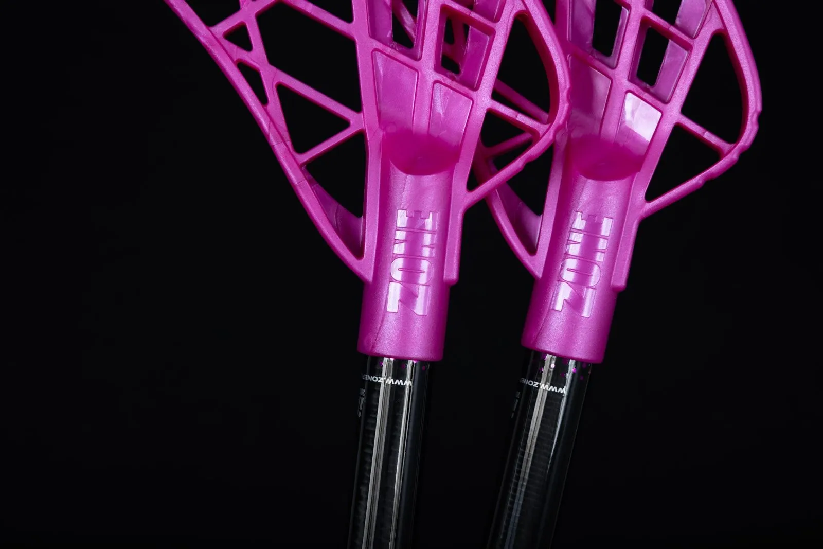 Two pink floorball stick blades against a black background