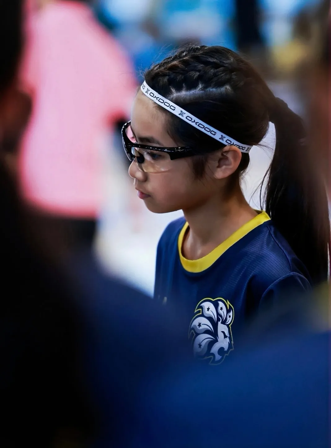 Profile of a girl with glasses and a white headband in a navy jersey