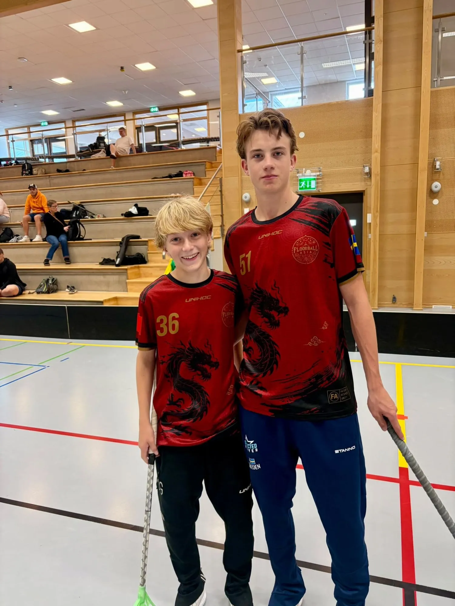 Two players in red dragon-design jerseys standing side by side in a sports hall